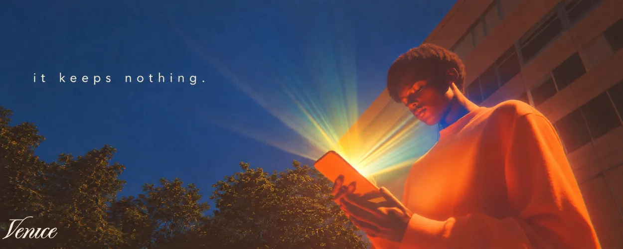 a person lit by a glowing phone under a blue sky with the line it keeps nothing