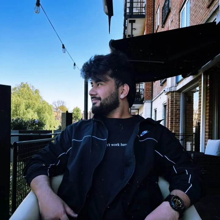 tanishq bodh sitting on a sunny balcony in a black nike jacket, looking to the side
